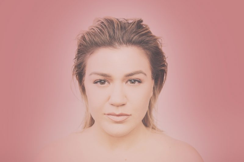 Kelly Clarkson em foto de divulgação de I Dare You, fundo rosa e pouca maquiagem