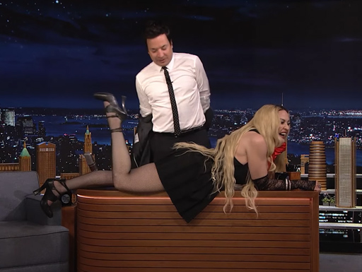 Madonna sensualiza e deita na bancada de apresentador de TV